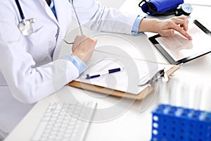 Doctor working table. Woman physician using tablet computer while sitting in hospital office close-up. Healthcare