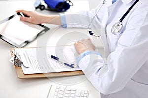 Doctor working table. Woman physician using tablet computer while sitting in hospital office close-up. Healthcare