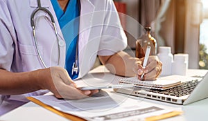 Doctor is working on a tablet and audio player and a digital tablet computer in a modern office.