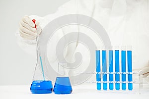 Doctor working on test tubes filled with blue liquid on the table in a medical laboratory
