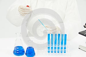 Doctor working on test tubes filled with blue liquid on the table in a medical laboratory