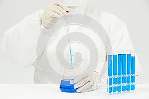 Doctor working on test tubes filled with blue liquid on the table in a medical laboratory