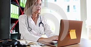 Doctor works on laptop keyboard in clinic