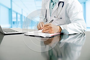 Doctor writes on documents at hospital office.