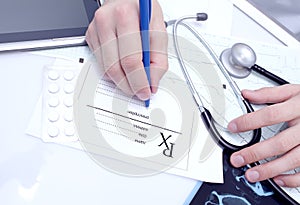 Doctor writes a prescription at his desk photo