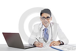 Doctor writes a prescription and looking at camera