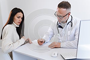 Doctor writes a prescription for medicines to his patient. Woman at the medical appointment.