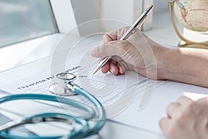 Doctor writing on medical health care record, patients discharge, or prescription form paperwork in hospital clinic
