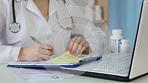 Doctor writing medical prescription, checking clinical records, signing papers