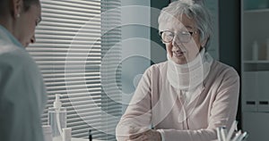 Doctor writing a medical prescription for an elderly patient