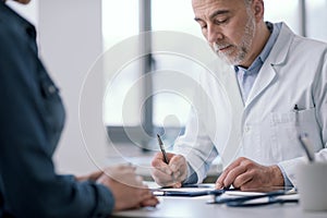 Doctor writing a medical prescription for his patient