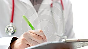 Doctor writing patient notes on a medical examination or prescription.