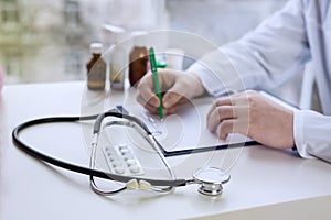 Male doctor writing patient notes on a medical examination or prescription