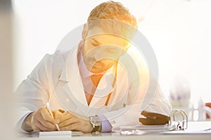 Doctor writing prescription at desk in hospital