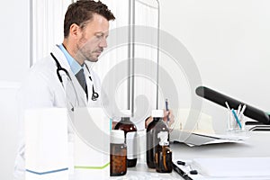 Doctor writing prescription at desk in medical office with drugs