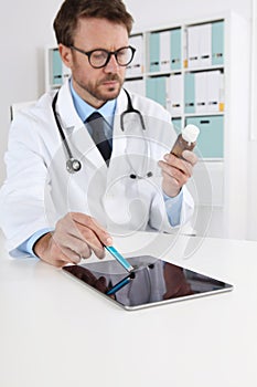 Doctor writing prescription in medical office with drugs touch digital tablet on desk