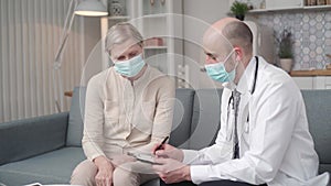 doctor writing a prescription to his patient during a home visit.