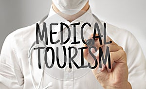 Doctor writing word MEDICAL TOURISM with marker, Medical concept