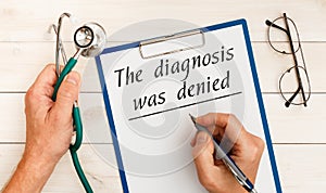 The doctor wrote - The diagnosis was denied, stethoscope, glasses, pen