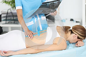 Doctor with Xray putting her hand on back of patient with kinesio tapes