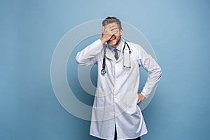 Doctor young man, medical professional terrified and nervous expressing anxiety and panic gesture, isolated over blue