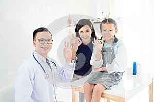 Doctor ,young patient girl with mother doing gesture Okay