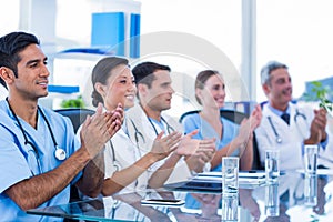 Doctors applauding while sitting at a table