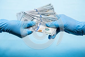 Doctors in blue gloves holds money cash dollars on blue background. Concept of bribe, corruption, profitshare or illegal