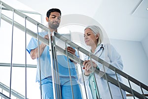 Doctors discussing over digital tablet while standing on stairs