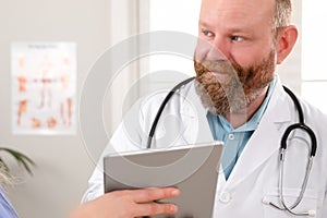 Doctors discussing report about a patient at tablet computer in hospital