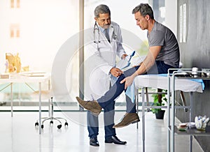 Doctors do it for the health of it. Shot of a mature doctor examining his patient who is concerned about his knee.