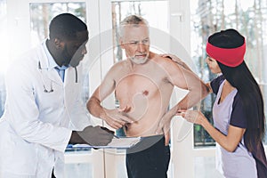 Doctors examine an elderly man who has a backache in his back.