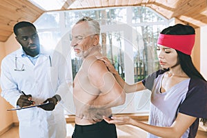 Doctors examine an elderly man who has a backache in his back.