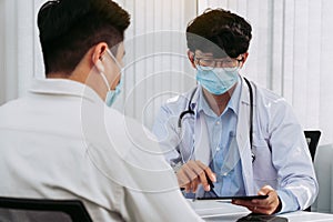 Doctors are explaining the treatment of a sick patient in tablets while wearing a mask during the virus outbreak