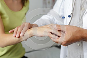 doctors hand checking female patient finger