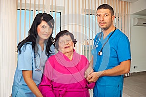 Doctors helping elderly woman patient