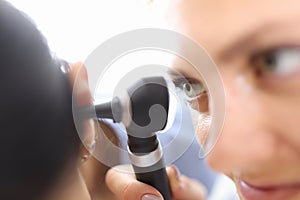 Doctors holding otoscope near patients ear in clinic close-up