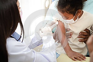 Doctors inject a vaccine in the arm of a young African-American girl to strengthen immunity and protect it from diseases.