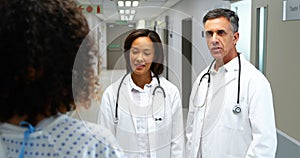 Doctors interacting with pregnant woman in corridor