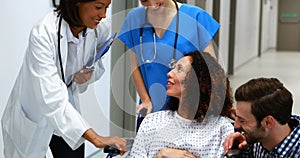 Doctors interacting with pregnant woman in corridor