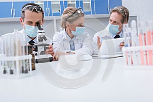 Scientists working with digital tablet and microscope