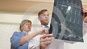 Doctors, a man and a woman analyze the results of MRI , x-ray images. the results of magnetic resonance therapy on film.