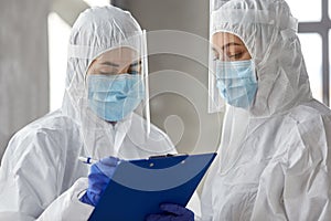 Doctors in medical mask and shield with clipboard