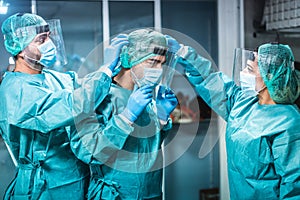 Doctors and nurse preparing to work in hospital for surgical operation during coronavirus outbreak - Focus on center man hand