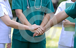 Doctors and nurses in a medical team stacking hands outdoor on t