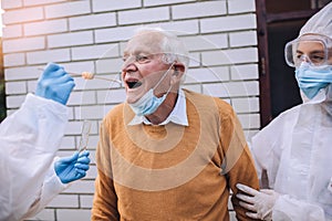 Doctors in a protective suit taking swab from a senior man to test for possible coronavirus infection