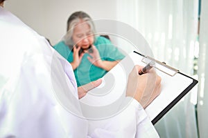 Doctors record treatment records for elderly patients sitting in wheelchairs.