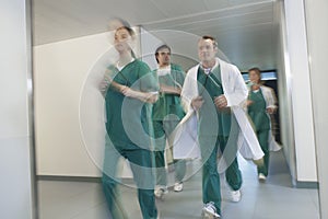 Doctors In Scrubs Running Through Hospital Corridor