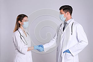 Doctors shaking hands on light grey background