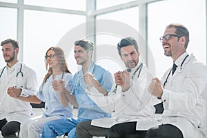 Doctors sit in a row and hold hands of each other